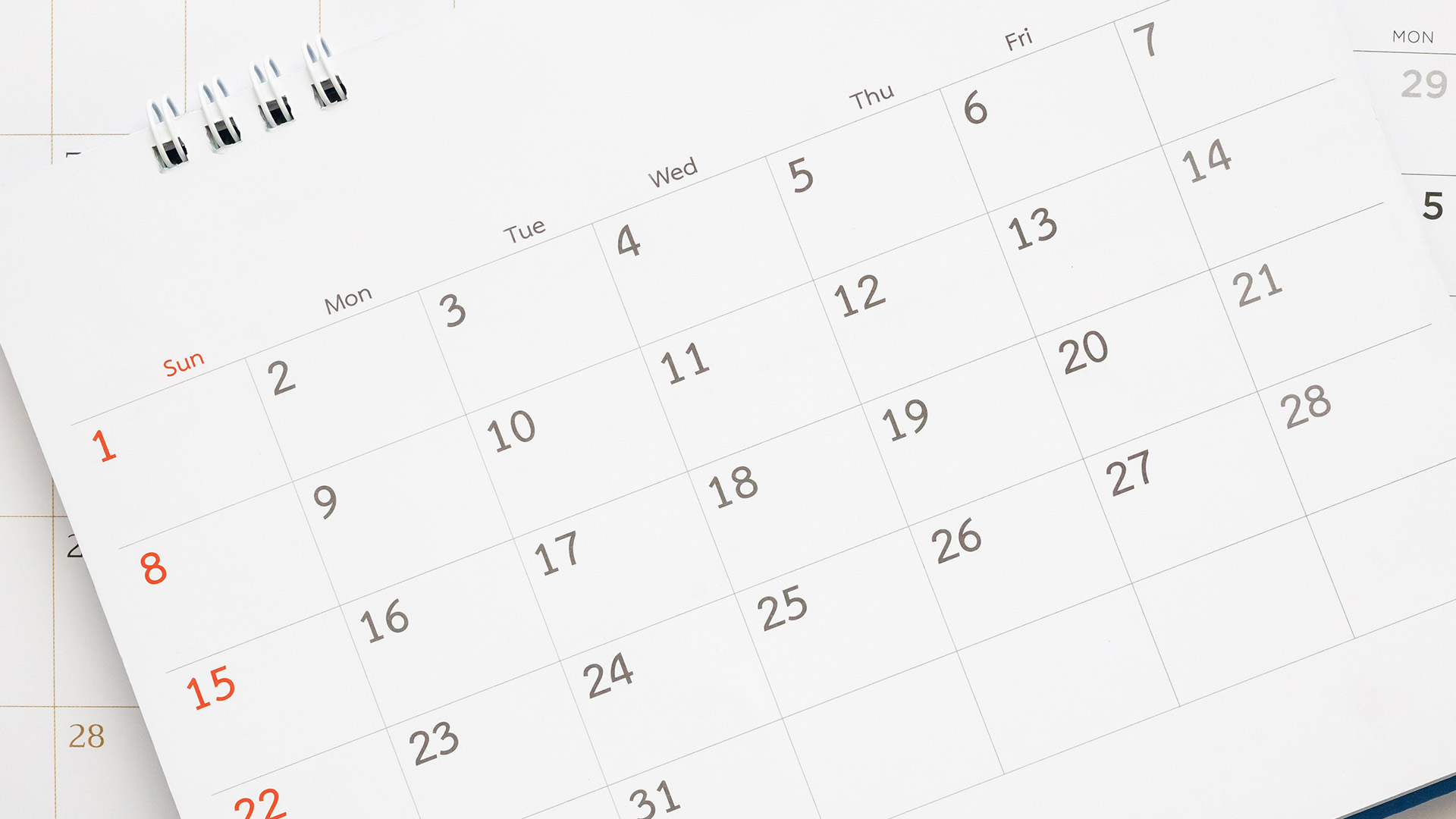 The image shows a white calendar with black text displaying dates from July to December 2023, placed next to a pen on a surface with a blurred background.