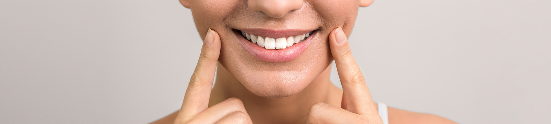 An individual with a smiling expression, making a playful gesture with their fingers near their mouth.