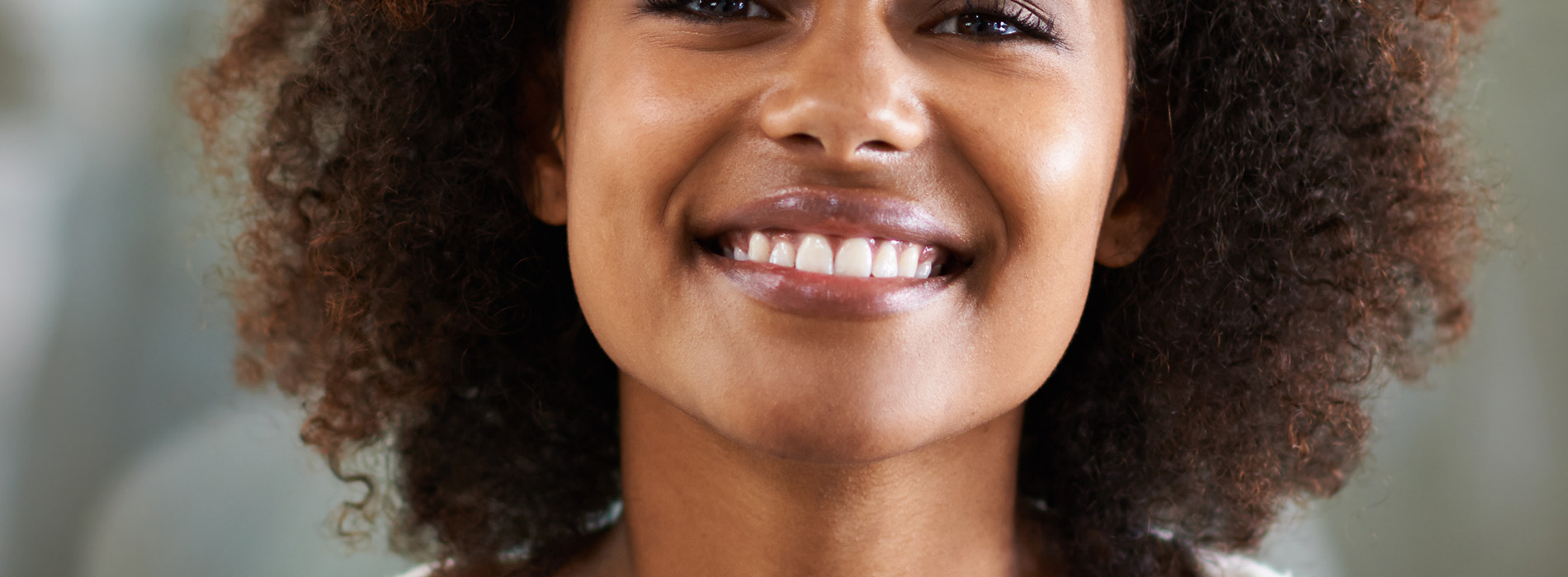 The image shows a woman with short hair smiling at the camera, overlaid with a digital effect that creates a pattern of smaller images of her face.