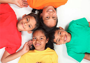 The image shows five children posing together with smiles on their faces  they are wearing colorful shirts and appear to be participating in a group photo session.