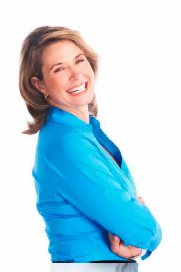 A woman with blonde hair, wearing a blue top, stands against a white background, smiling slightly while leaning on her left hand.