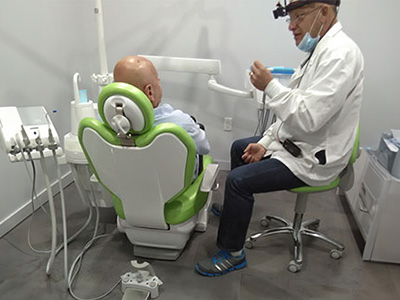 A dentist performing a procedure on a patient with dental equipment.