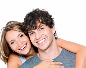 The image shows a man and woman posing closely together with smiles on their faces  they appear to be a couple sharing a happy moment.