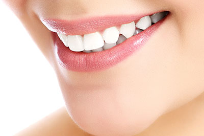 The image features a close-up of a person s face, focusing on their teeth, which are enhanced with a whitening treatment, as indicated by the brightness and contrast around the treated area.