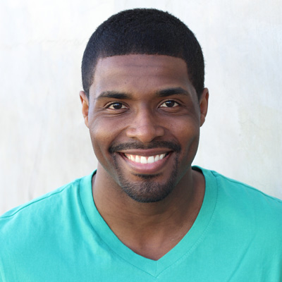 A middle-aged couple posing together with smiles, embracing each other outdoors during daylight.