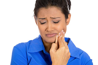 A woman with a concerned expression, looking upwards with her hand near her mouth, possibly brushing her teeth or about to brush them.