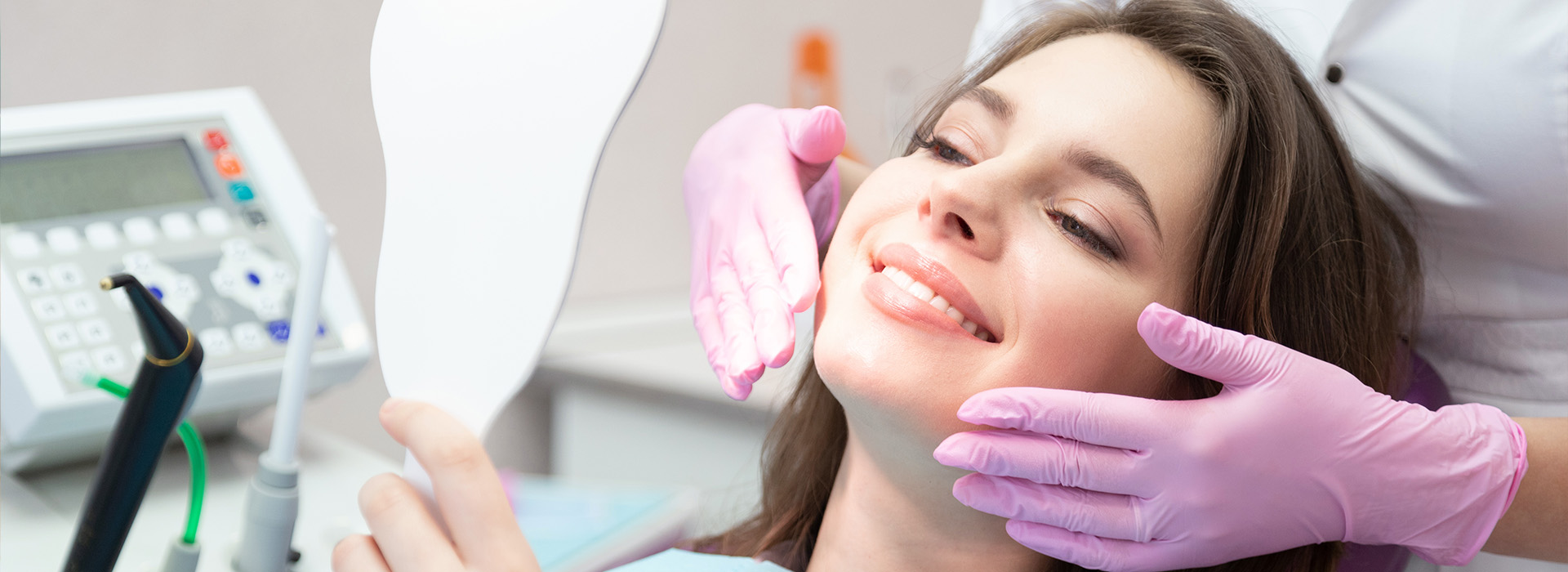 A woman sitting in a dental chair with a dentist examining her teeth.