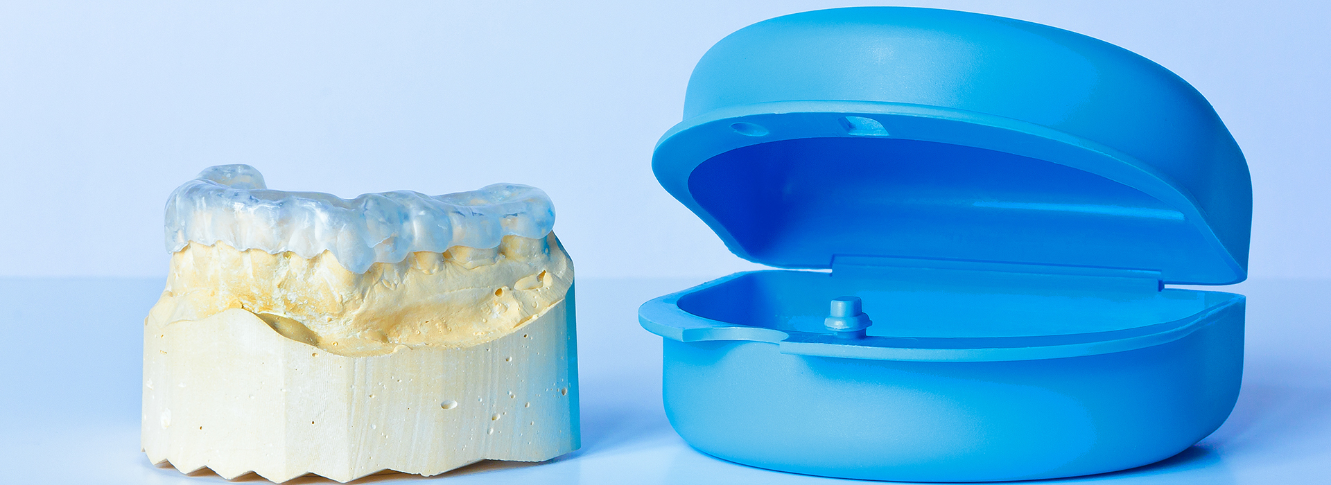 The image shows a blue dental model on the right side and a yellow dental implant on the left, both placed against a white background.