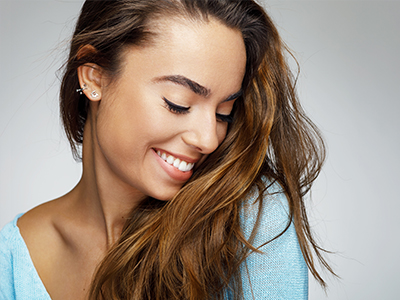 The image shows a woman with long hair smiling at the camera.