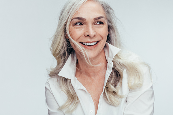 A woman with short blonde hair smiles at the camera while looking off to her left.