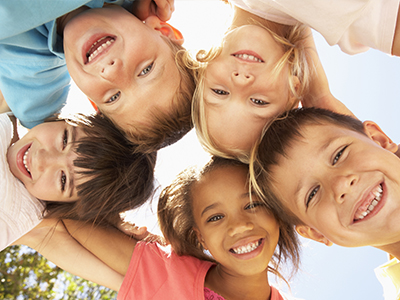 A group of children with their arms around each other, smiling at the camera.